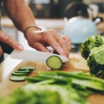 Hands,,Cutting,Board,And,Salad,In,Kitchen,With,Green,Vegetables