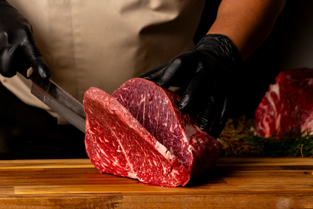 The,Butcher,Wearing,Black,Gloves,Cuts,The,Meat,With,Knife